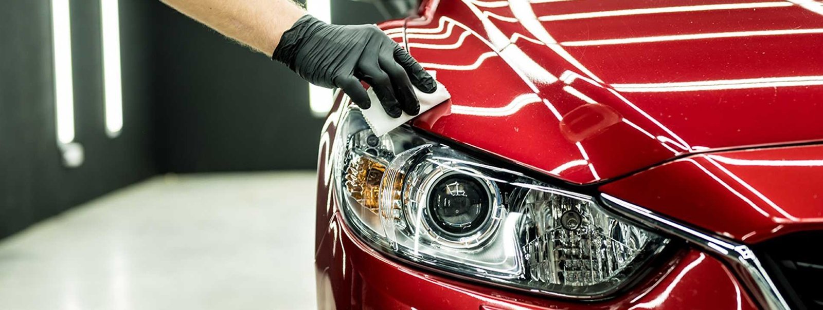 Gloved detailer applying ceramic coating to a car panel in a professional studio